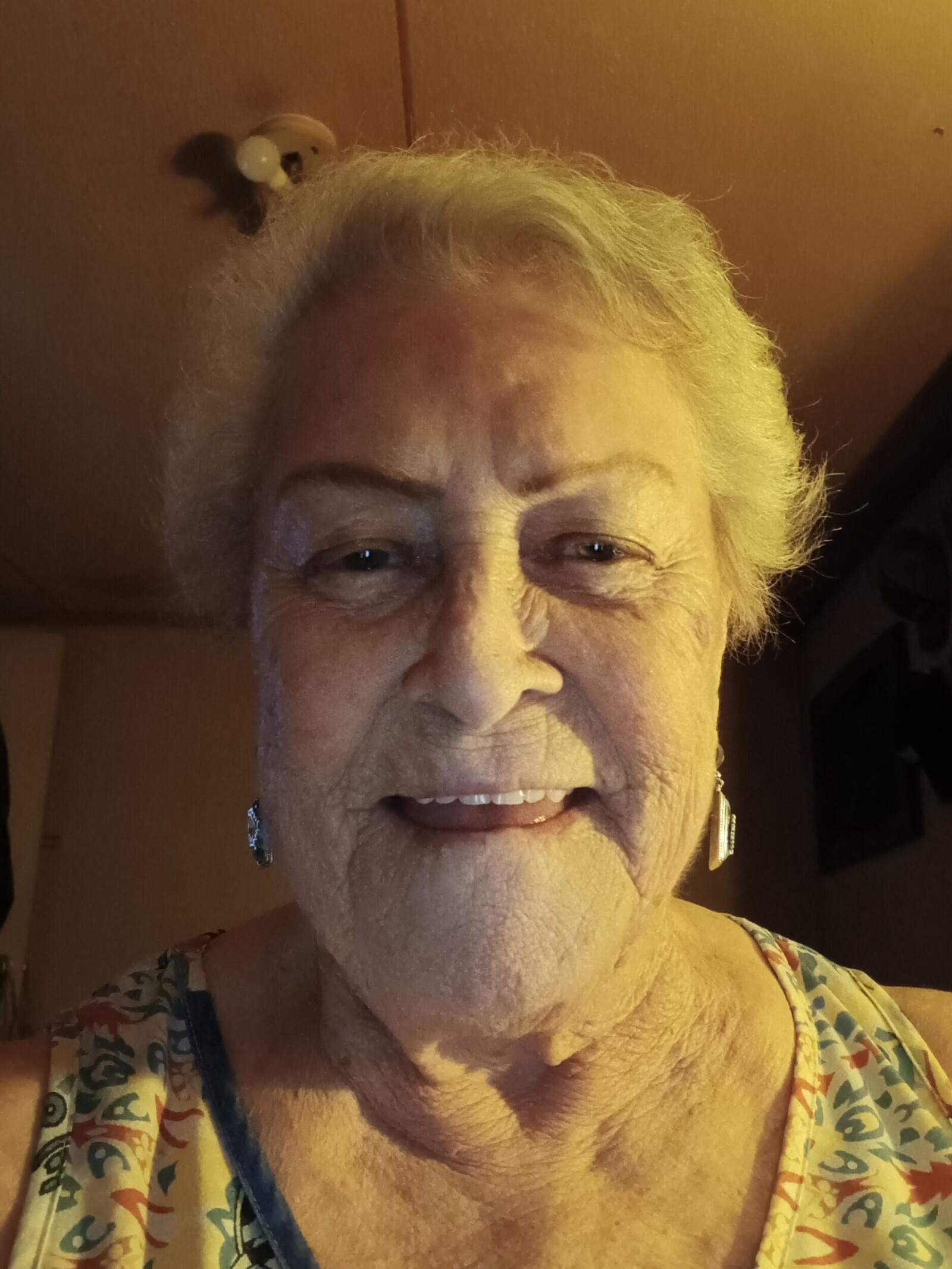 Portrait of Dee Russell, an older woman with short white hair, smiling at the camera.