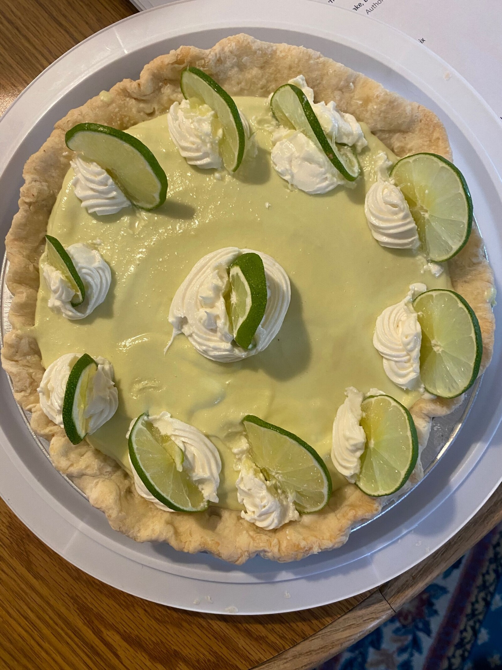 Key-lime pie with a pale green filling, whipped cream, and fresh lime slices.